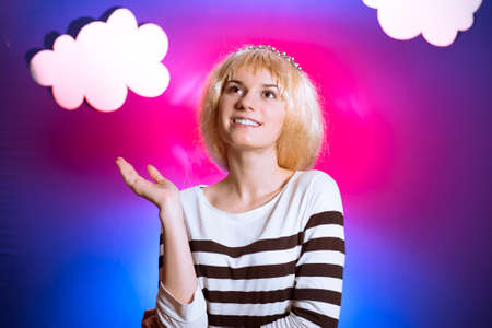 Portrait of beautiful exciting young woman in blond wig. Pretty girl happy smiling on blue and...