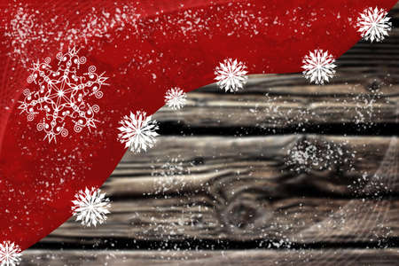 Picture of white snowflakes on dark red background beside oak plank table top. Artistic digital winter theme image.の写真素材