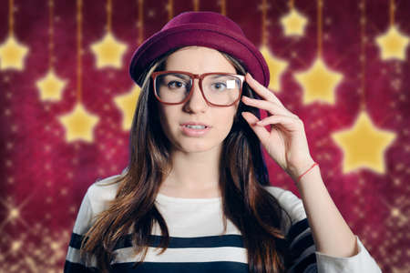 Double exposure photo of young pensive female wearing red hat touching her hipster glasses on bright purple background with graphic shining starsの写真素材