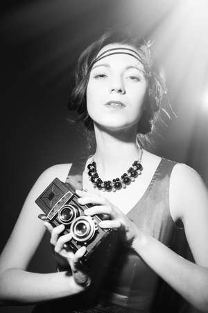 Black and white photography of beautiful elegant lady holding retro film cameraの写真素材