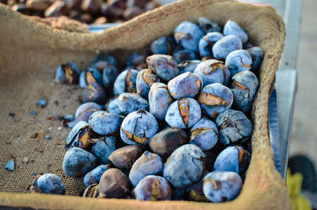Closeup photo of appetizing grilled chestnuts with peeling shell in jute sackの写真素材