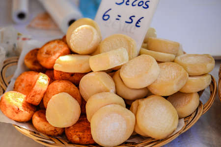 Closeup photo of delicious homemade sheep cheese on wooden plate with price tag standing on market standの写真素材