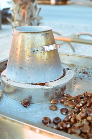Photo of cooking chestnuts in special iron pan on outdoor backgroundの写真素材