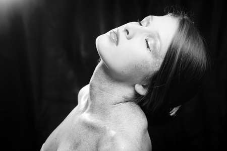 Black and white portrait of covered in shining make up sexy beautiful young woman with eyes closed relaxing on black backgroundの写真素材