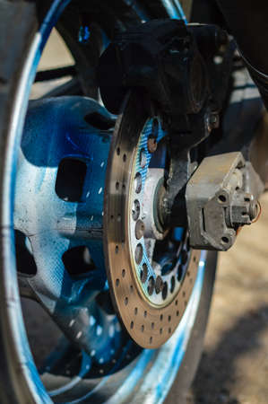 Closeup color shot of a front wheel motorbike forks and tire on sunny outdoors backgroundの写真素材