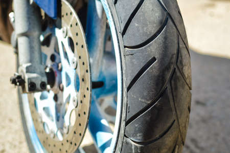 Closeup color shot of a front wheel motorbike forks and tire on sunny outdoors background