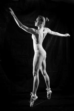 Black and white photography silhouette of beautiful young lady on dark background in dancing poseの写真素材