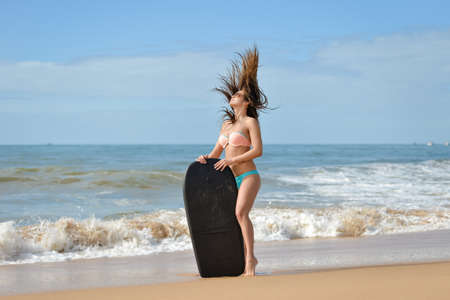 Picture of beautiful girl at the beach with her bodyboard, ready for fun. Beach background sunny...