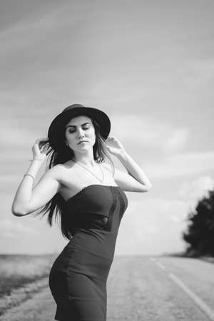 Black and white photography of beautiful elegant girl in hat on a sunny summer day outdoors backgroundの写真素材
