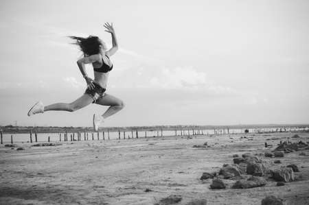 Black and white photography of dance and jump, female silhouette on outdoors background. Dawn sky