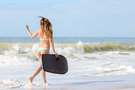 Picture of beautiful girl at the beach with her bodyboard, ready for fun. Beach background sunny blue sky on tropical exotic locationの写真素材