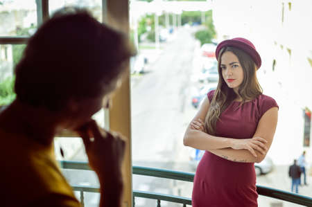 Portrait of beautiful young couple having conversation while looking at each other over a window...
