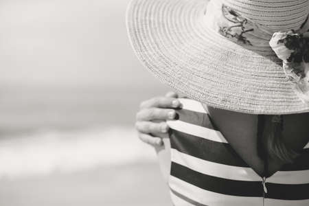Black and white photo of beautiful romantic lady enjoying summer beach and sun, looking at sea. Back viewの写真素材