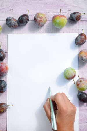 Top view on hand writing letter, plum fruits wooden background, closeupの写真素材