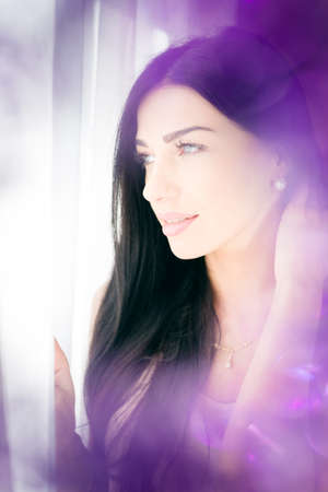Beautiful young lady looking at the window. Closeup portrait