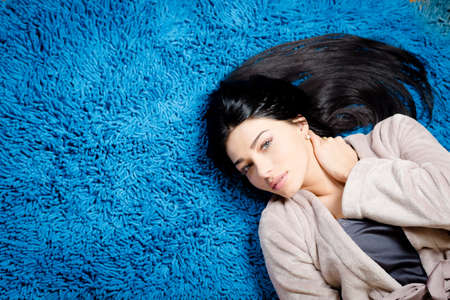 Portrait of beautiful young female having fun relaxing on blue carpet copy space background