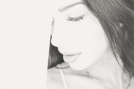 Black white photography of beautiful young lady looking at the window. Closeup portrait