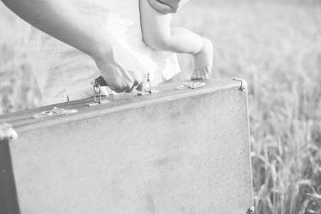 Black and white photography closeup of father's hand holding old suitcase and toddlerの写真素材