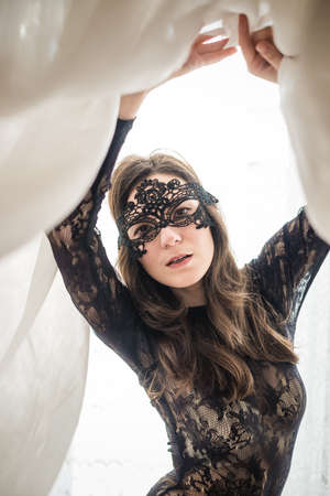 Portrait of sensual woman with lace mask on light window backgroundの写真素材