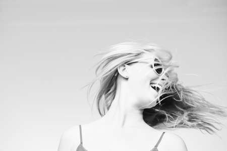 Black and white photography of amazing joyful sensual young female with flying blonde hair over sky...