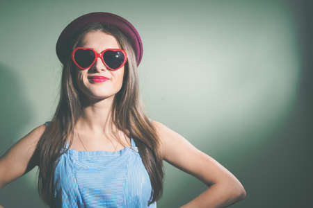 Beautiful elegant girl with sunglasses and hat on light background indoors