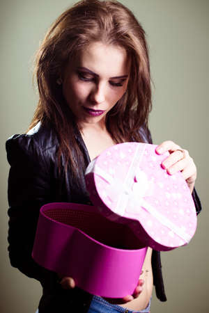Portrait of beautiful glamorous woman with hands holding love heart shape gift box on light backgroundの写真素材