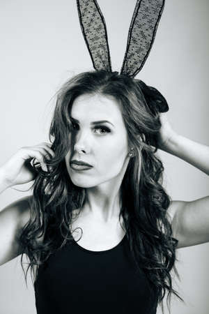 Sexy beautiful woman in bunny ears mask relaxing on light bed background alone