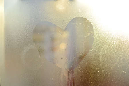 Blurry abstract heart drawn on condensation window glass background