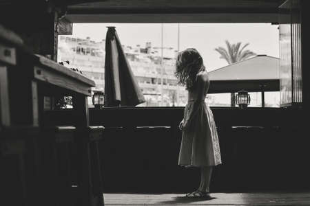Black and white portrait of moody female standing up over light window backgroundの写真素材