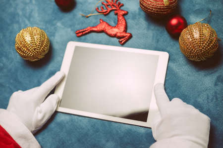 Smart Santa Claus working using smartphone on busy table surface background . Close up top view on screen. Merry Christmas, Love and Happy New Year festive designの写真素材