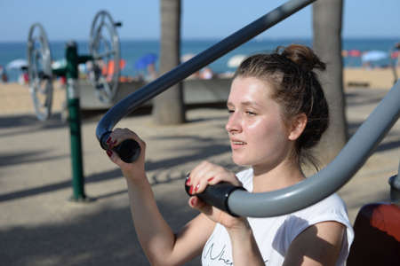 Woman doing fitness street workout on the sunny outdoors sports ground background