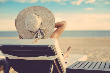 Rear view of joyful happy beautiful female on a tropical beach blue sky outdoors backgroundの写真素材