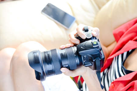 Person working with DSLR camera and smartphone, light background. Close up top view screen mockup