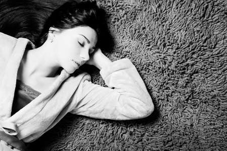 Black and white picture of beautiful young woman laying on fluffy soft carpet indoor backgroundの写真素材