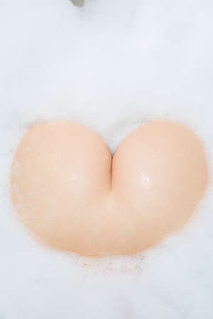 Closeup on unrecognizable seductive beautiful young woman buttocks on spa bath foam backgroundの写真素材