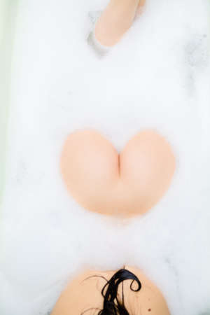 Closeup on unrecognizable seductive beautiful young woman buttocks on spa bath foam backgroundの写真素材