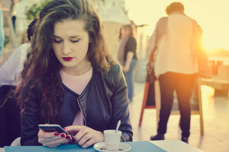 Woman sitting in restaurant cafe table on sunny outdoors backgroundの写真素材