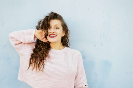 Joyful cheerful woman gesturing on light wall background