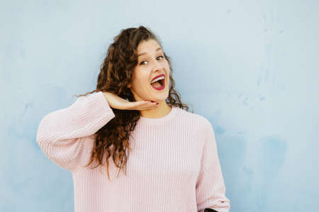 Joyful cheerful woman gesturing on light wall backgroundの写真素材