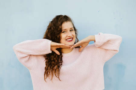 Joyful cheerful woman gesturing on light wall backgroundの写真素材