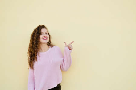 Joyful cheerful woman gesturing on light wall backgroundの写真素材