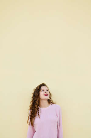 Joyful cheerful woman gesturing on light wall backgroundの写真素材
