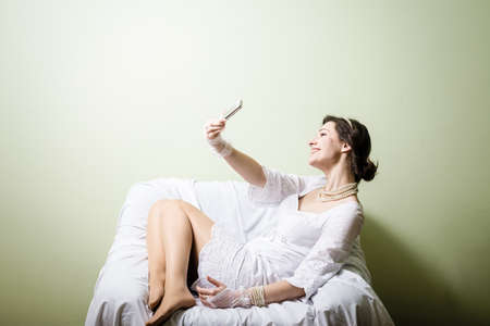 Happy joyful woman using mobile smartphone on light chair background. Portraitの写真素材
