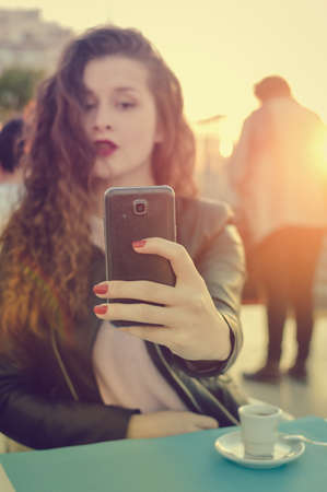 Attractive woman using smart mobile phone in cafe or restaurant, sunny outdoors background