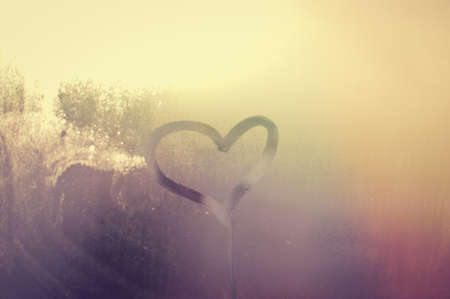 A love heart painted on a misted glass window background. Close up photo of lovely emotional mood drawの写真素材