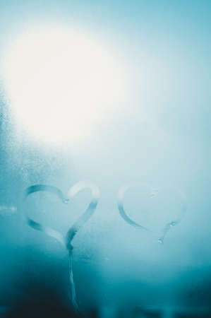 2 love hearts painted on a misted glass window background. Close up photo of lovely emotional mood drawの写真素材