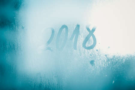 2018 painted on a misted glass window background. Close up photo of New Year drawの写真素材