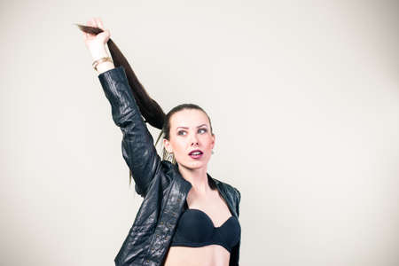 Portrait of beautiful glamorous woman in black leather jacket on light background