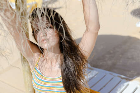 Holiday vacation leisure lifestyle. Beautiful girl having fun relaxing on sunny lounge beach summer outdoor background. Portrait of sensual relaxation under sun parasolの写真素材
