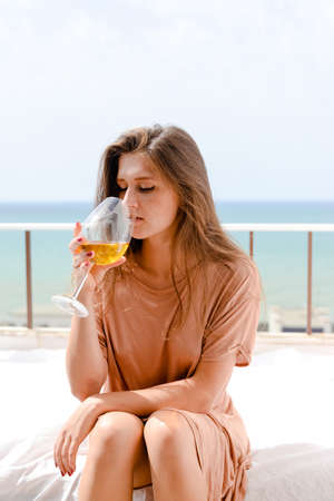 Beautiful woman luxury relaxing enjoying drink glass of wine on blue sky sea outdoors background